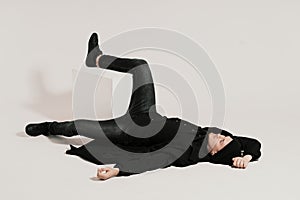 Fashionable man lying on white background with a leg on a cube