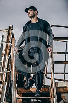 Fashionable man in urban setting in metal rusty ladle