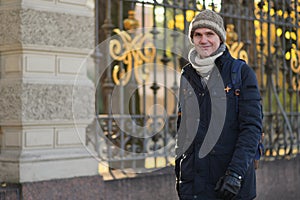 Fashionable man walking along  black cast iron fence