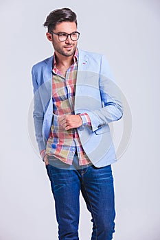 Fashionable man walking in studio with hand in back pocket