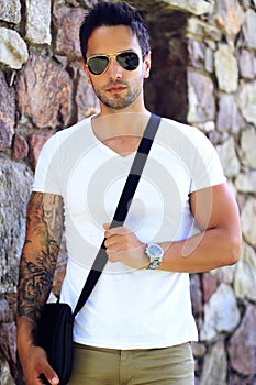 Fashionable man wearing satchel bag, watch ans sunglasses .