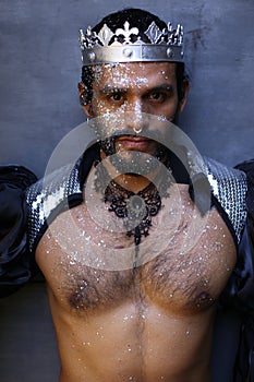 Fashionable man wearing silver glitter body art and a crown