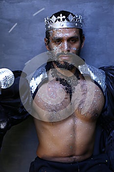Fashionable man wearing silver glitter body art and a crown