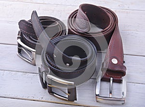 Fashionable men`s leather belt. Gadgets and accessories for men on light wooden background.