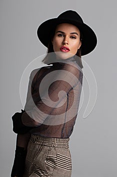 Fashionable model in hat posing in studio during test shoot