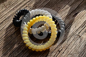 Fashionable and modern elastic hair springs. Different colors of stretching hand bracelets on wooden background,