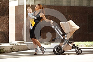 Fashionable modern mother on a city street with a pram. Young mo