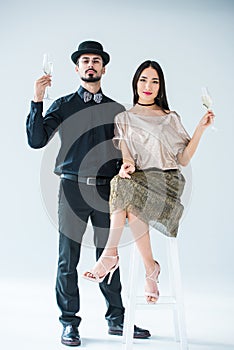 fashionable multicultural couple with glasses of champagne looking at camera