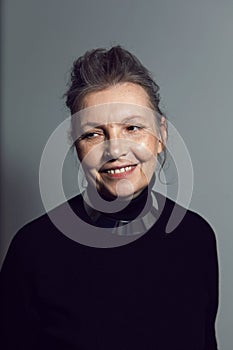 fashionable older woman in black clothes stands against a white