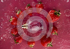 Fashionable perfume bottle and ripe juicy strawberries in spray of water