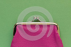 Fashionable pink wallet on a light green background. Close up