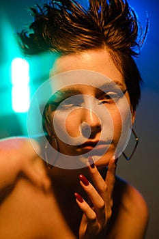 Fashionable portrait of emotional young beautiful woman with raised up short hair. Colorful fashionable neon light, blue