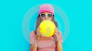 Fashionable portrait stylish cool young woman inflating chewing gum wearing pink hat on blue background