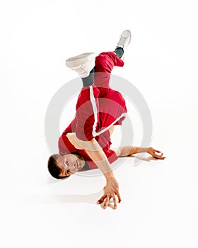 Fashionable portrait. Stylishly dressed young man dancing twist element in freestyle, break dance in motion against