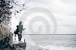 Fashionable portrait of a young brunette woman in black clothes, jeans T-shirt, coat and sunglasses, in a Gothic style sad mood