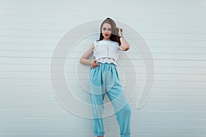 Fashionable pretty young brunette woman in stylish elegant clothes posing outdoors in the city near the vintage wall. Attractive