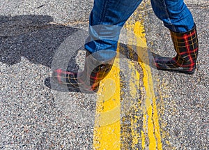 Fashionable rubber boots walking across a highway