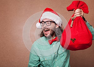 Fashionable Santa Claus derided holding a bag with gifts