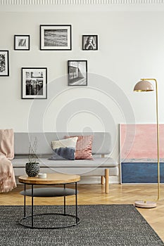 Fashionable settee with pillows in bright living room interior with pastel pink and blue painting