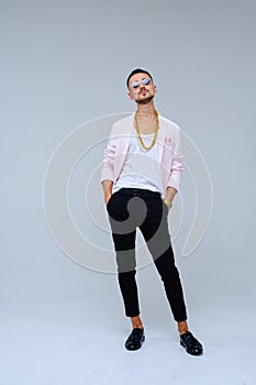 Fashionable sophisticated man in a pink jacket and black trousers, wears a gold chain, the expression of emotions gestures with