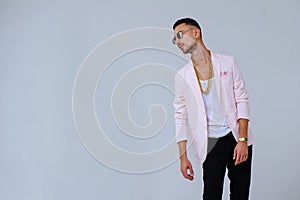 Fashionable sophisticated man in a pink jacket and black trousers, wears a gold chain, the expression of emotions gestures with