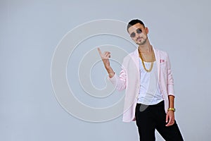 Fashionable sophisticated man in a pink jacket and black trousers, wears a gold chain, the manifestation of emotions gestures hand