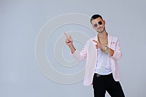Fashionable sophisticated man in a pink jacket and black trousers, wears a gold chain, the manifestation of emotions gestures hand