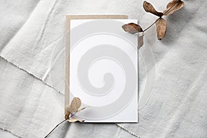 Fashionable stock stationery background - white card for lettering and dry plants and flowers on a white table.