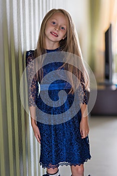 Fashionable style of clothes for children. Little little girl wearing a beautiful lace blue dress. Girl model with long hair