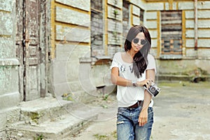 Fashionable stylish girl with old camera wearing sunglasses and