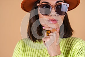 Fashionable stylish woman on a beige background in a sweater and hat