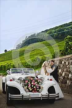 Fashionable and stylish young couple near the retro car, blonde girl in a lace dress and handsome man in trendy