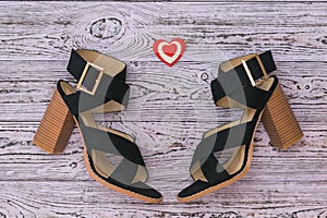 Fashionable suede women`s shoes and a heart on a wooden background. Flat lay.