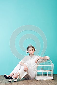 fashionable teenager in white with parrot in cage