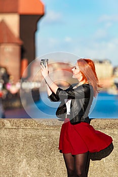 Fashionable tourist girl taking picture with camera old town Gdansk