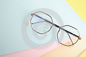 fashionable trendy eyes glasses for vision correction on a colorful background, geometric background from pastel paper