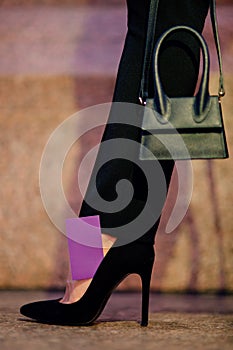 Fashionable woman inside, holding small black bag, wearing stylish heels, elegant clothes. Female fashion concept. Copy