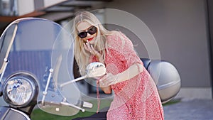 Fashionable Woman Leaning on a Vintage Scooter Outdoors photo