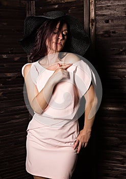 Fashionable woman posing in wide-brimmed black hat. Woman in elegant outfit. Woman fashionable brunette stands on a
