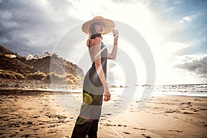 Fashionable woman on a sunset walk on the beach. Summer island vibes