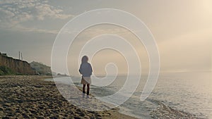 Fashionable woman walking on sea shore. Relaxed girl enjoying ocean landscape.