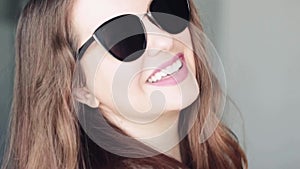 Fashionable woman wearing stylish sunglasses and smiling, beauty face portrait of a caucasian european model as fashion