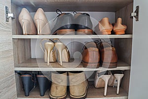 Fashionable women high heels and leather men shoes in wooden cabinet for going to work