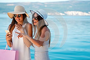 Fashionable women out on the street with shopping bags enjoying summer vacation and travel.