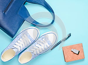 Fashionable women& x27;s accessories and devices on a gray background: usb flash drive, bag, wallet, sneakers, pen. Top view.