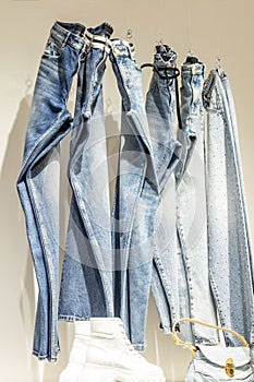 Fashionable women's jeans hang on a showcase in a store. Style, comfort and beauty. Vertical