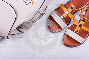 Fashionable women`s sandals and backpack on white wooden background