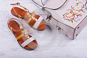 Fashionable women`s sandals and backpack on white wooden background