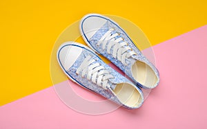 Fashionable women& x27;s sneakers with white laces from the 80s on a yellow pink pastel background. Top view.