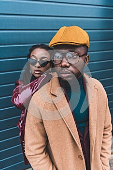 fashionable young african american couple in jacket and overcoat posing together